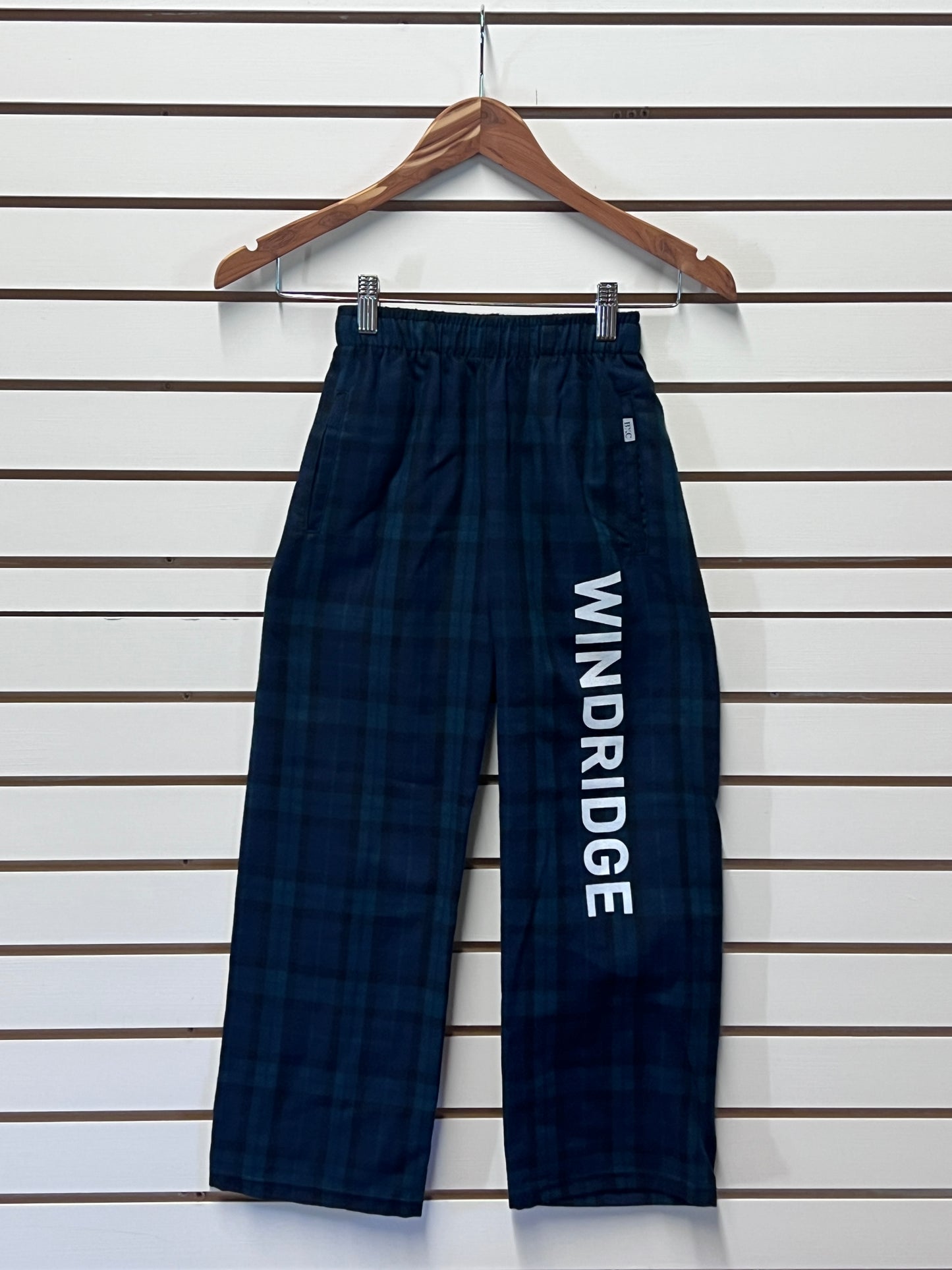 Navy blue plaid pants with 'WINDRIDGE' branding on a wooden hanger against a white background