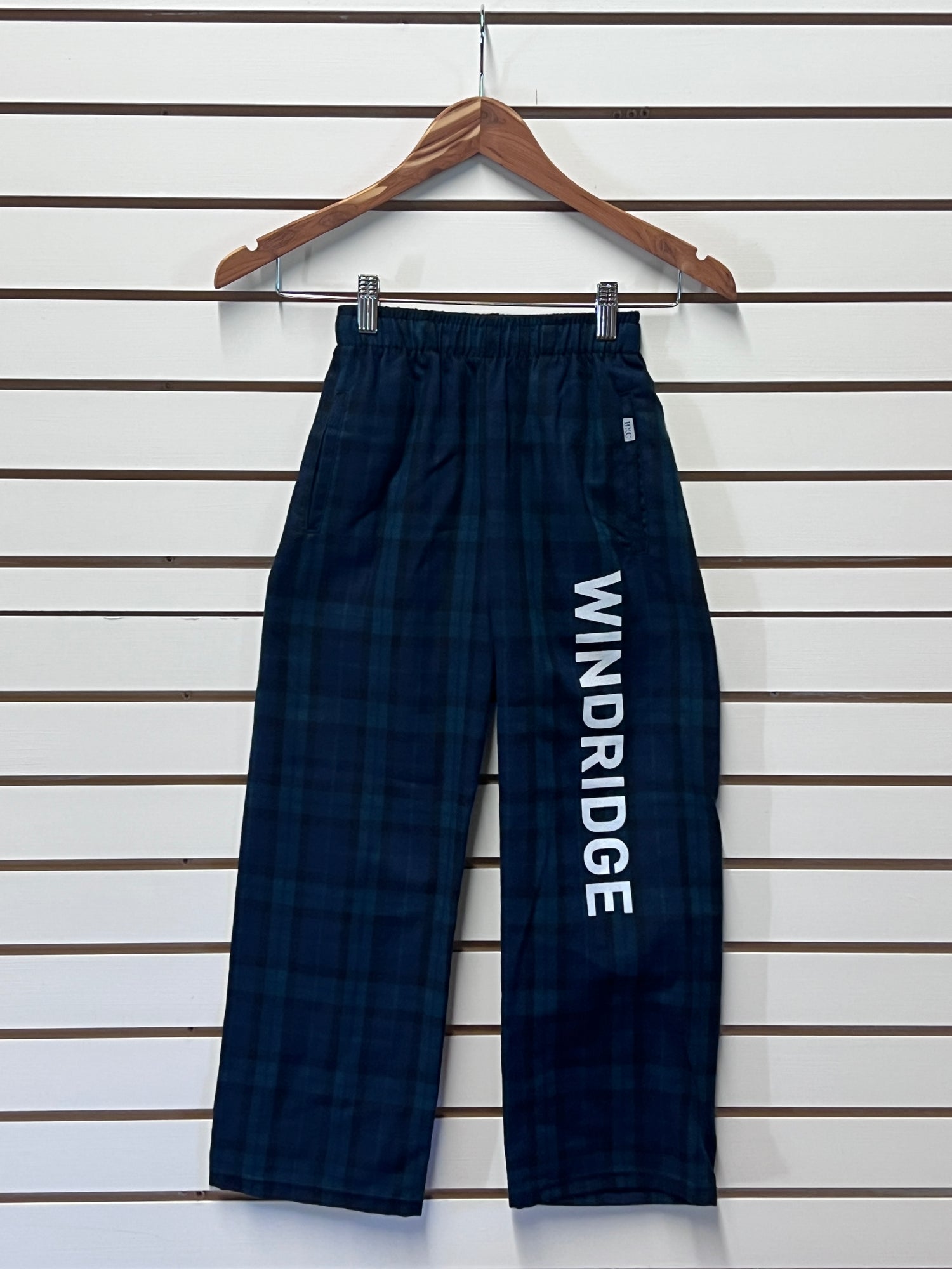 Navy blue plaid pants with 'WINDRIDGE' branding on a wooden hanger against a white background